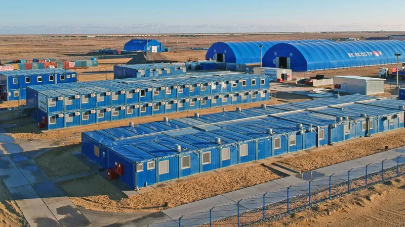 CGCH worker camp deployed on a desert oil & gas site for Russian operator Velesstroy — blue containers and arched warehouses on sand
