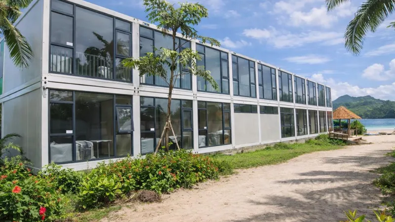 CGCH beachfront 2-story modular resort with floor-to-ceiling glass facade, palm trees, and tropical coastline
